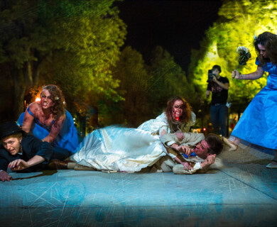 Individuals in Halloween costumes, including zombie brides, outdoors at night.