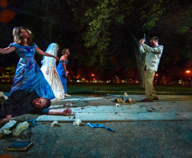 Nighttime park scene of confrontation, man with weapon, blood, prone person, women confronting.