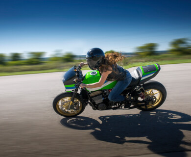 Person on a speeding green and black motorcycle with blurred surroundings on open road.