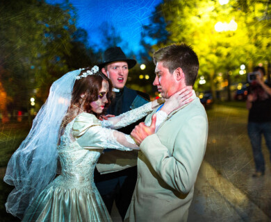 Bride in zombie makeup with man in street at night; another records the scene.