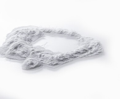 A mound of fine white powder is spread on a smooth, pale surface, forming an irregular circular shape. Irregular mound of fine white powder on a smooth pale surface.