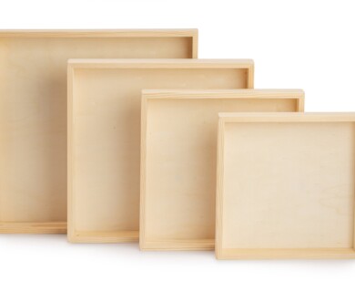 This image shows a set of four nested wooden frames, each progressively smaller, arranged in a row against a plain background. Four nested wooden frames of varying sizes on a plain backdrop.