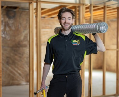 Person in uniform with duct tube in unfinished construction area.